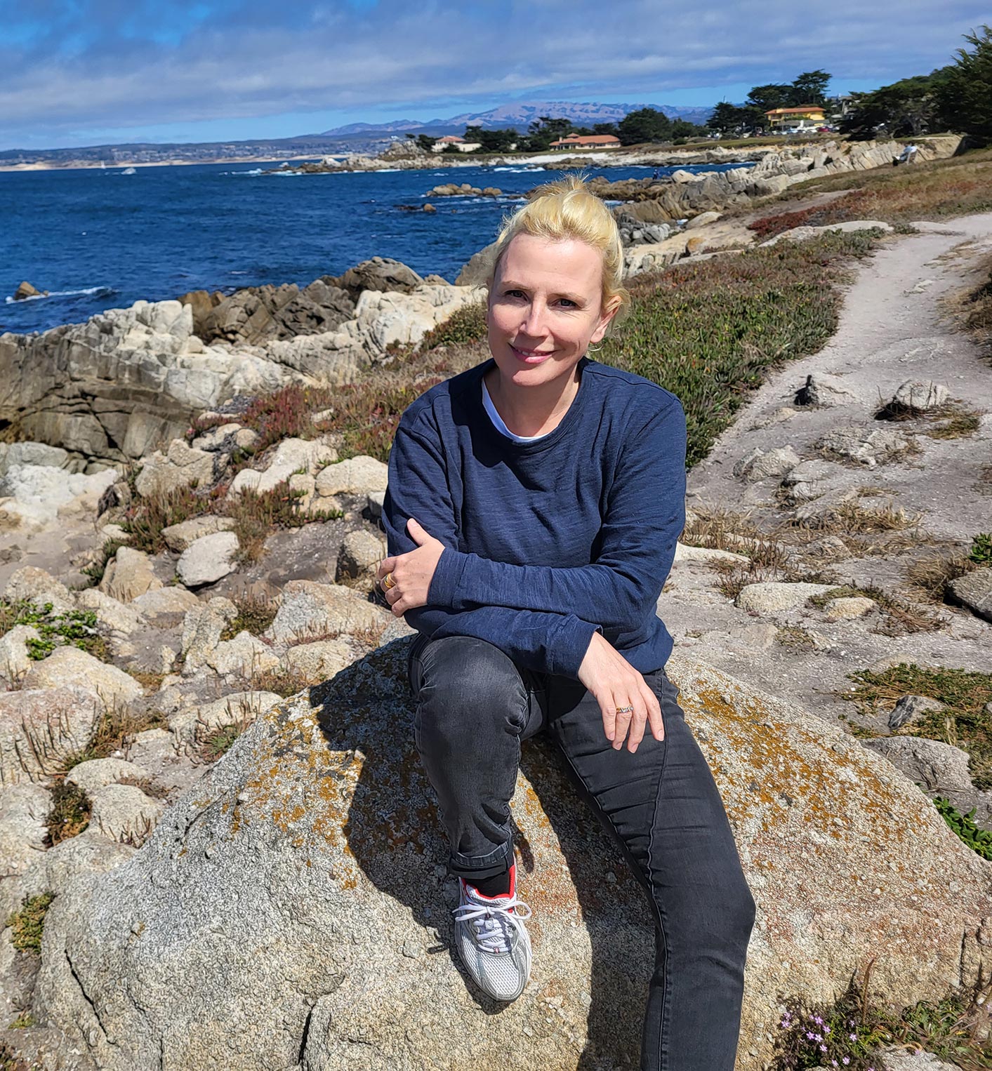 Katharina Schmidt sitzt auf Steinen vor dem Meer